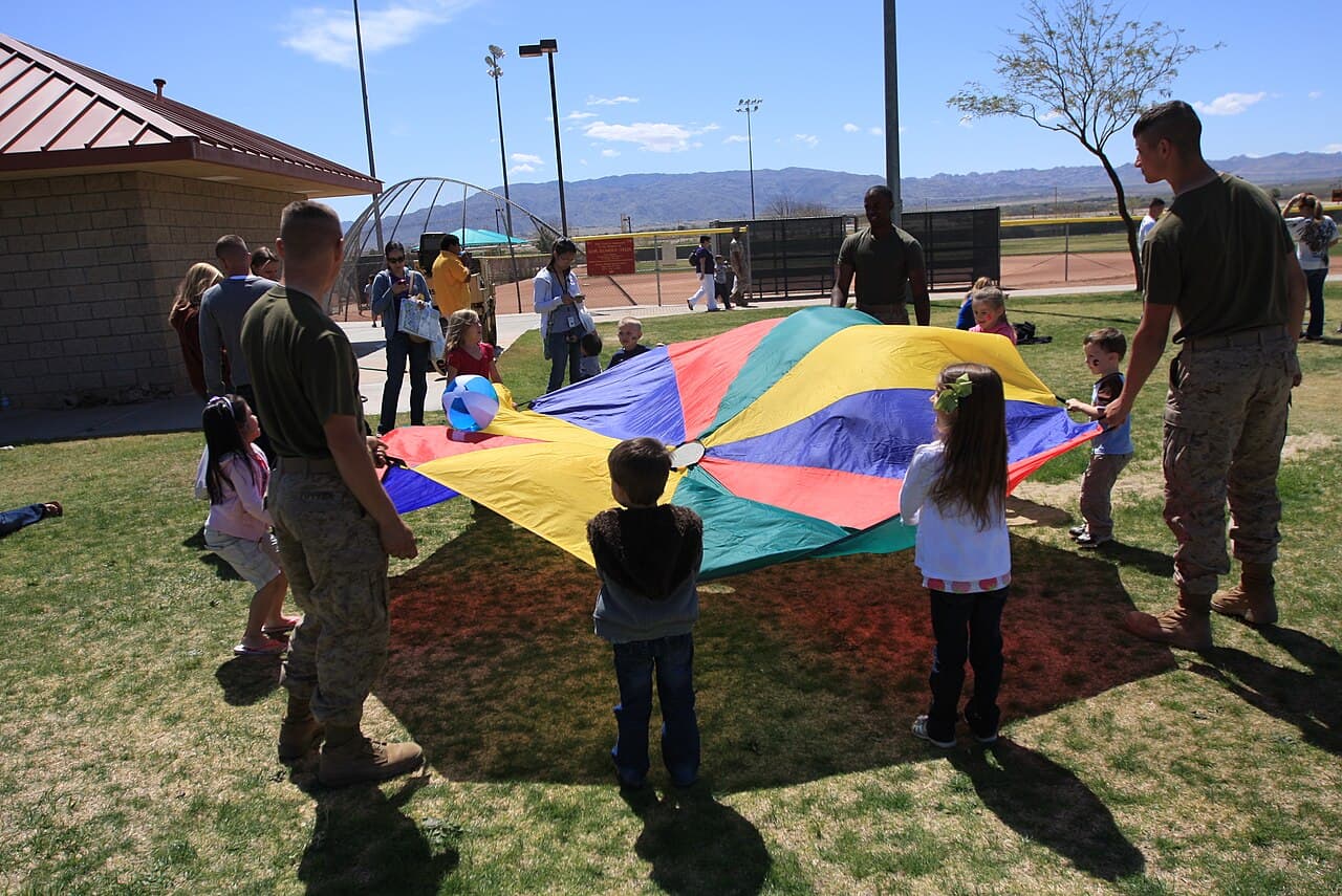 Children and adult leaders playing a cooperative parachute game outdoors